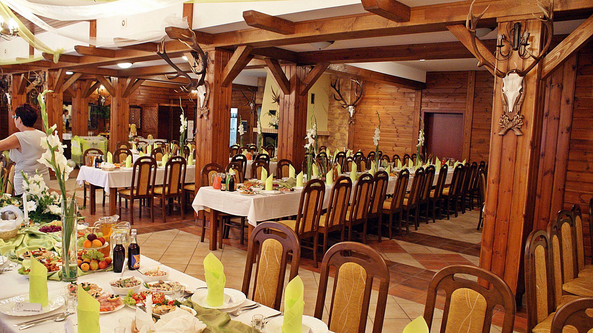 Long banquet table set with folded green napkins, plates and appetizers, festive atmosphere