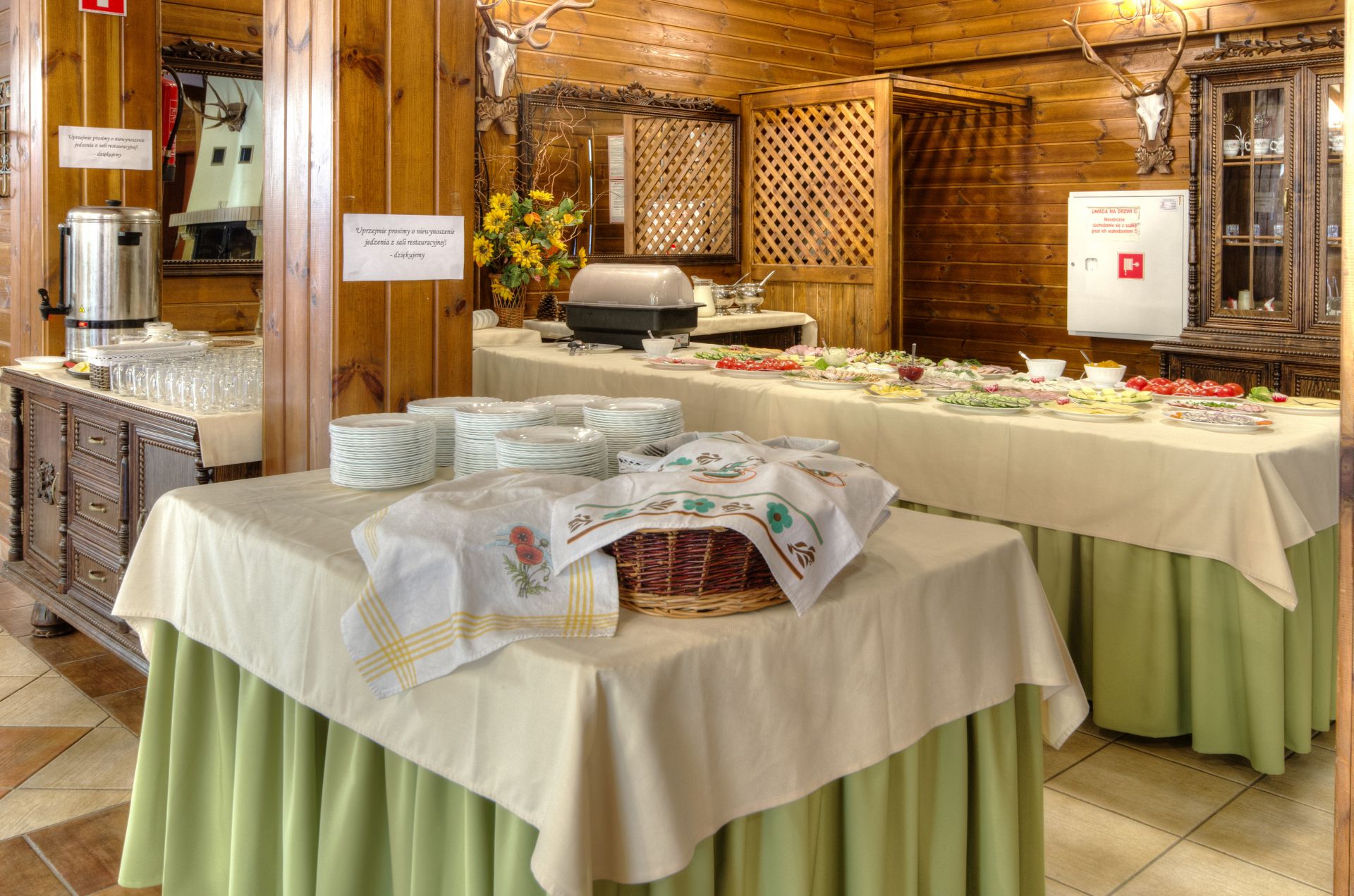 Buffet table close-up with glassware, pitchers, plates and covered chafing dish, ready
