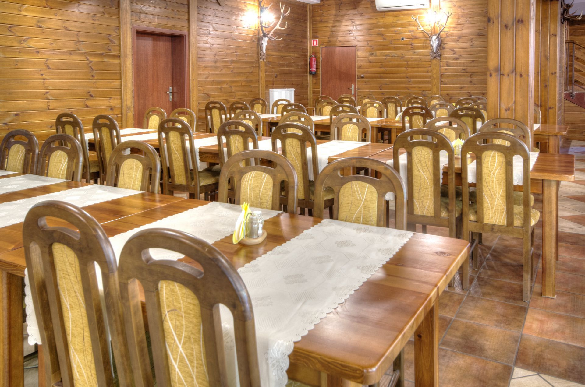Wide view of tiled floor and rows of wooden tables and chairs, calm dining space