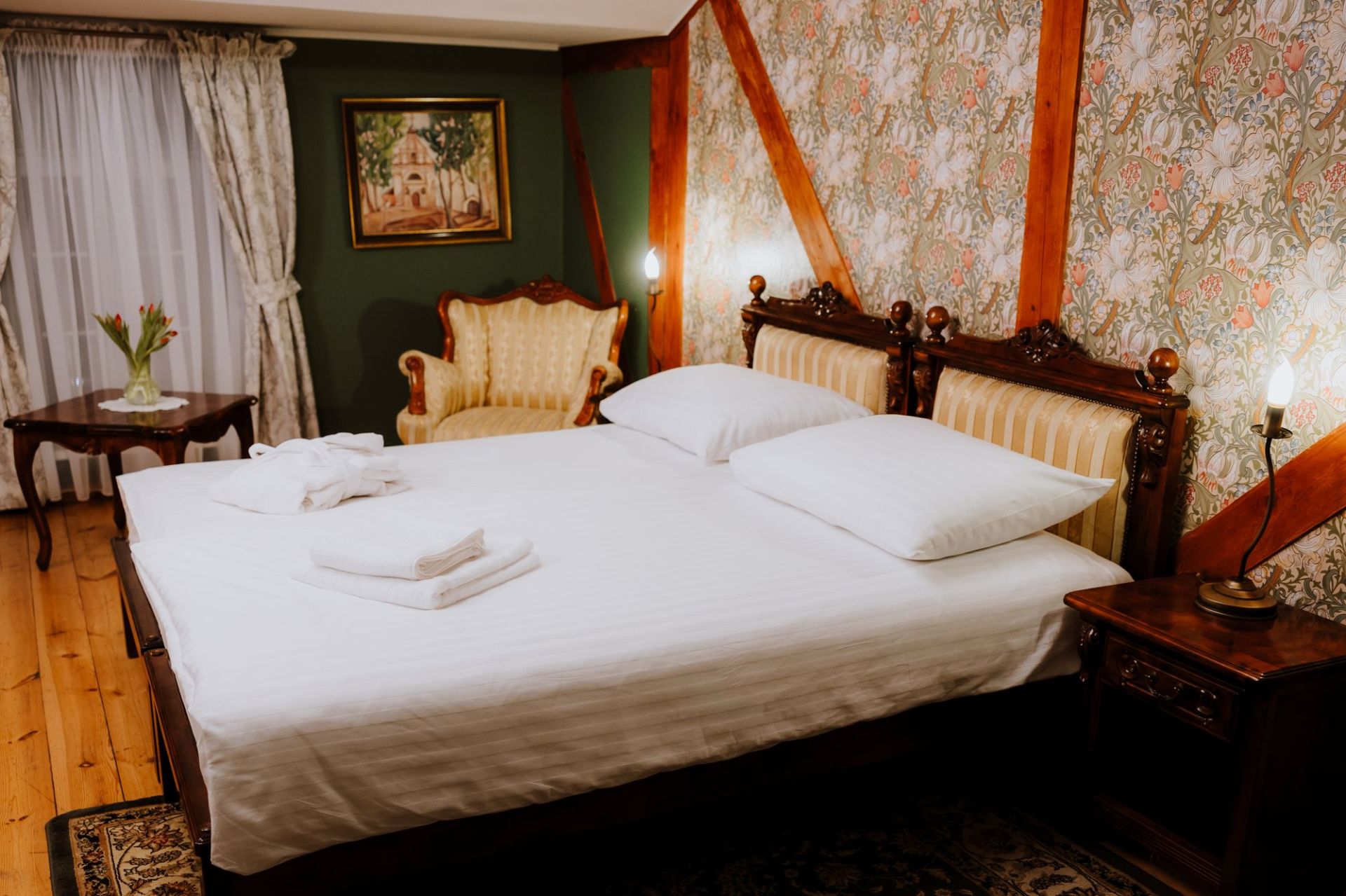Close view of neatly folded robes and towels on a made bed under soft lamp light.