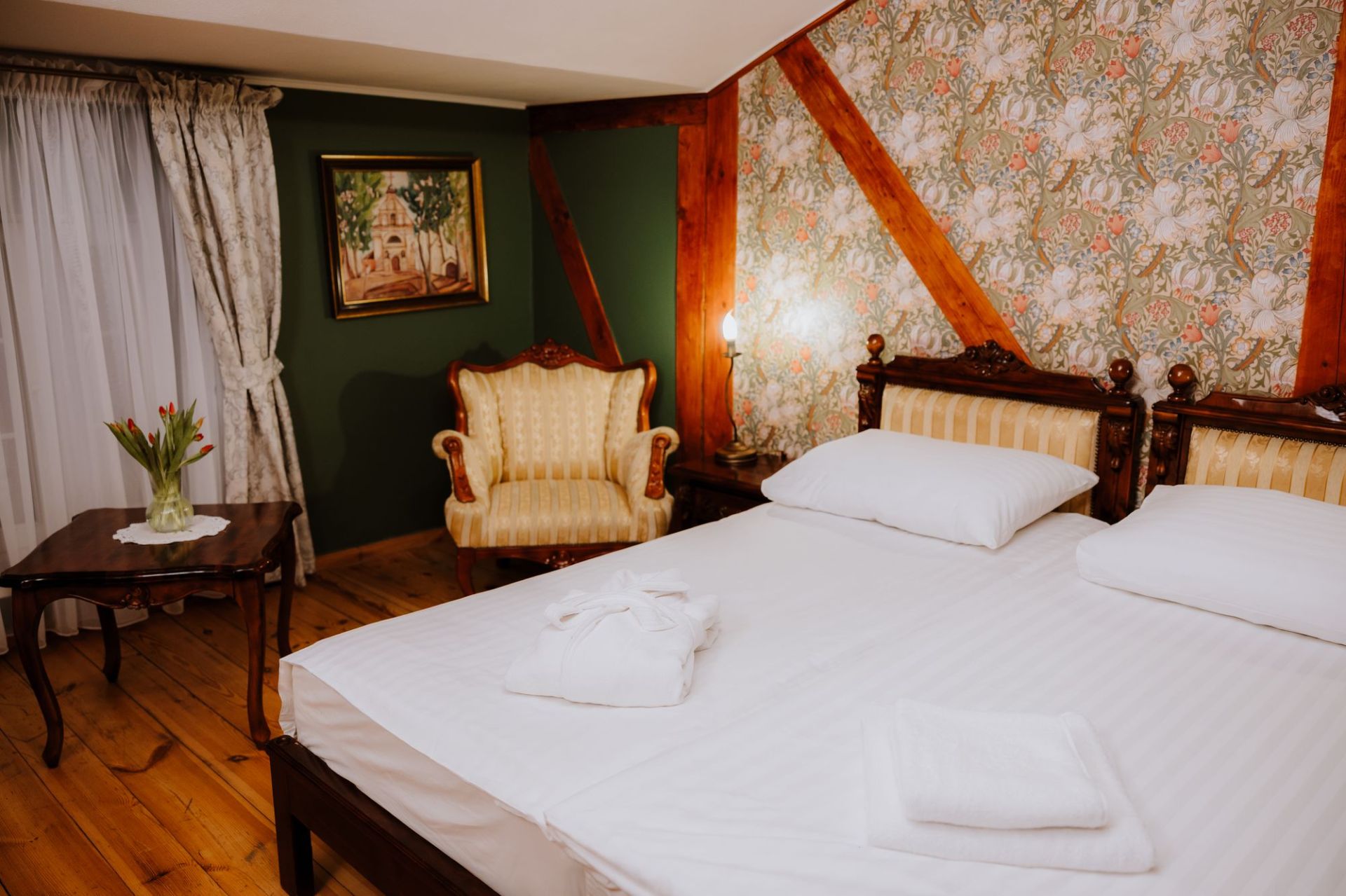 Two single mattresses with white linens, folded robe and towels arranged at the foot.