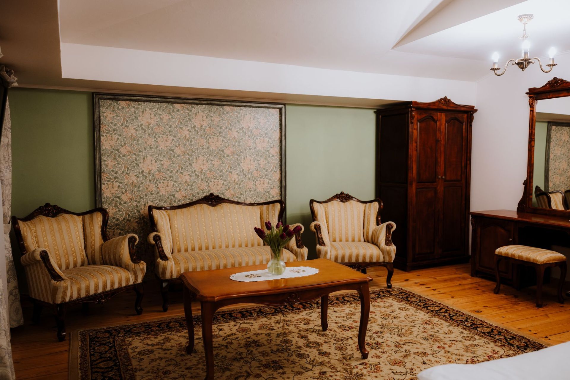 Vintage sitting area with striped sofa and armchairs, wooden coffee table and tulip vase.